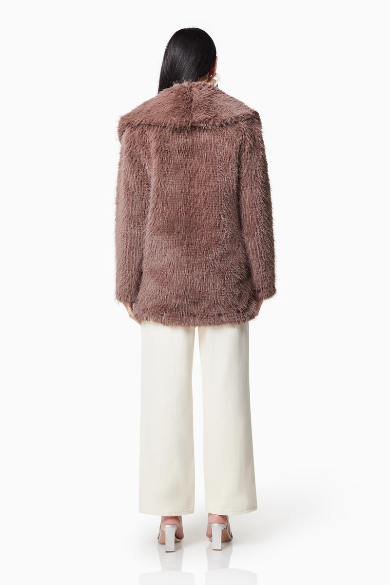Brunette model wearing WYOMING FAUX FUR COAT IN BROWN back shot