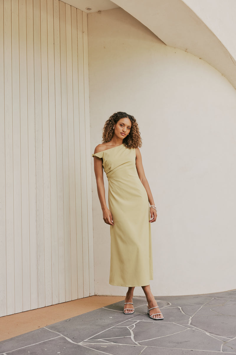 Brunette Model wears CURAAE Elenor Asymmetrical Summer Midi Dress In Olive front shot 