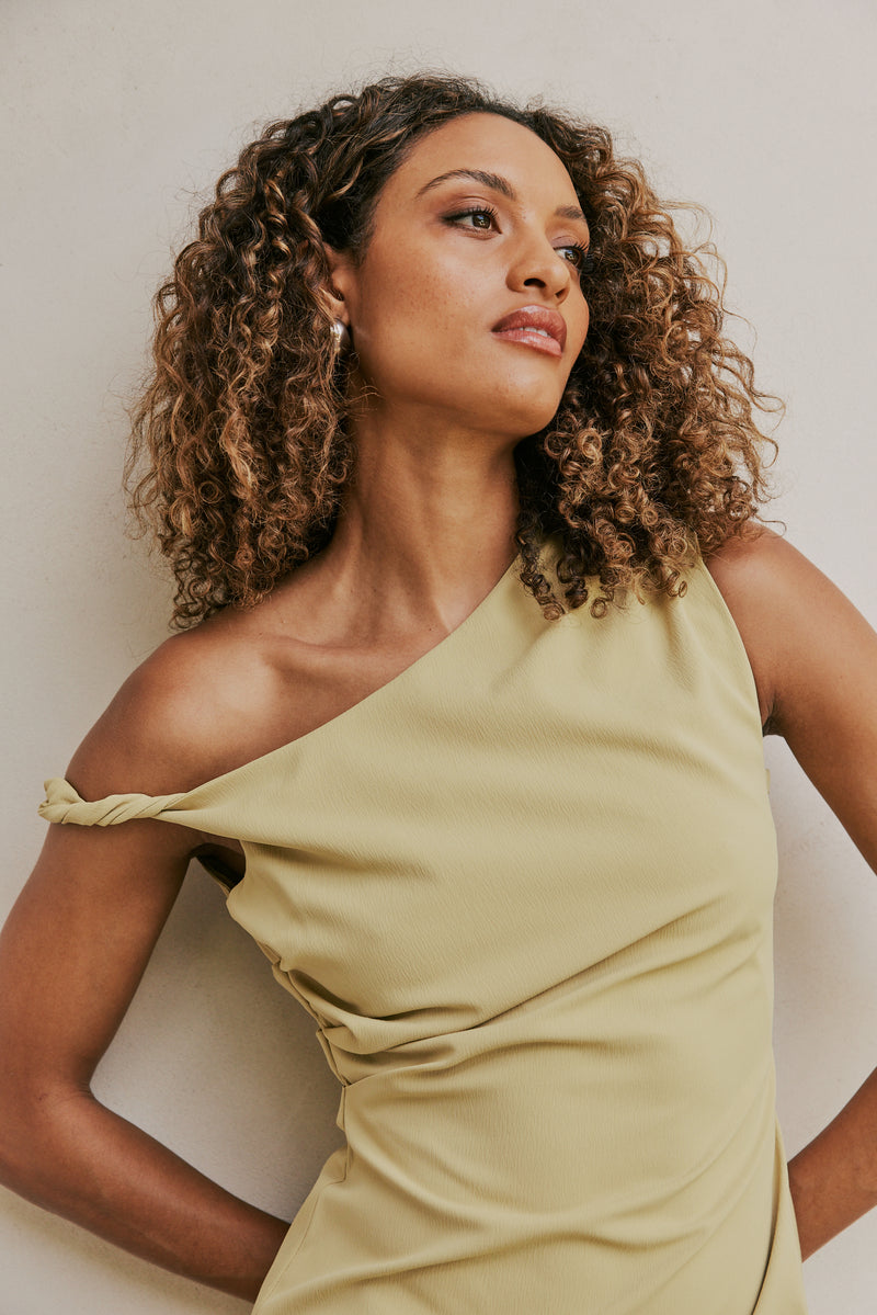 Brunette Model wears CURAAE Elenor Asymmetrical Summer Midi Dress In Olive mood shot 