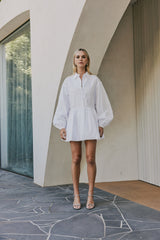 blonde model wears CURAAE Vienna Bubble Low Waist Skirt Long Sleeve Shirt Dress In White front shot