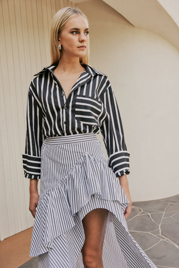 blonde model wears CURAAE Capri Midi Frill Asymmetrical High Waisted Skirt In Lilac & White Stripe mood shot