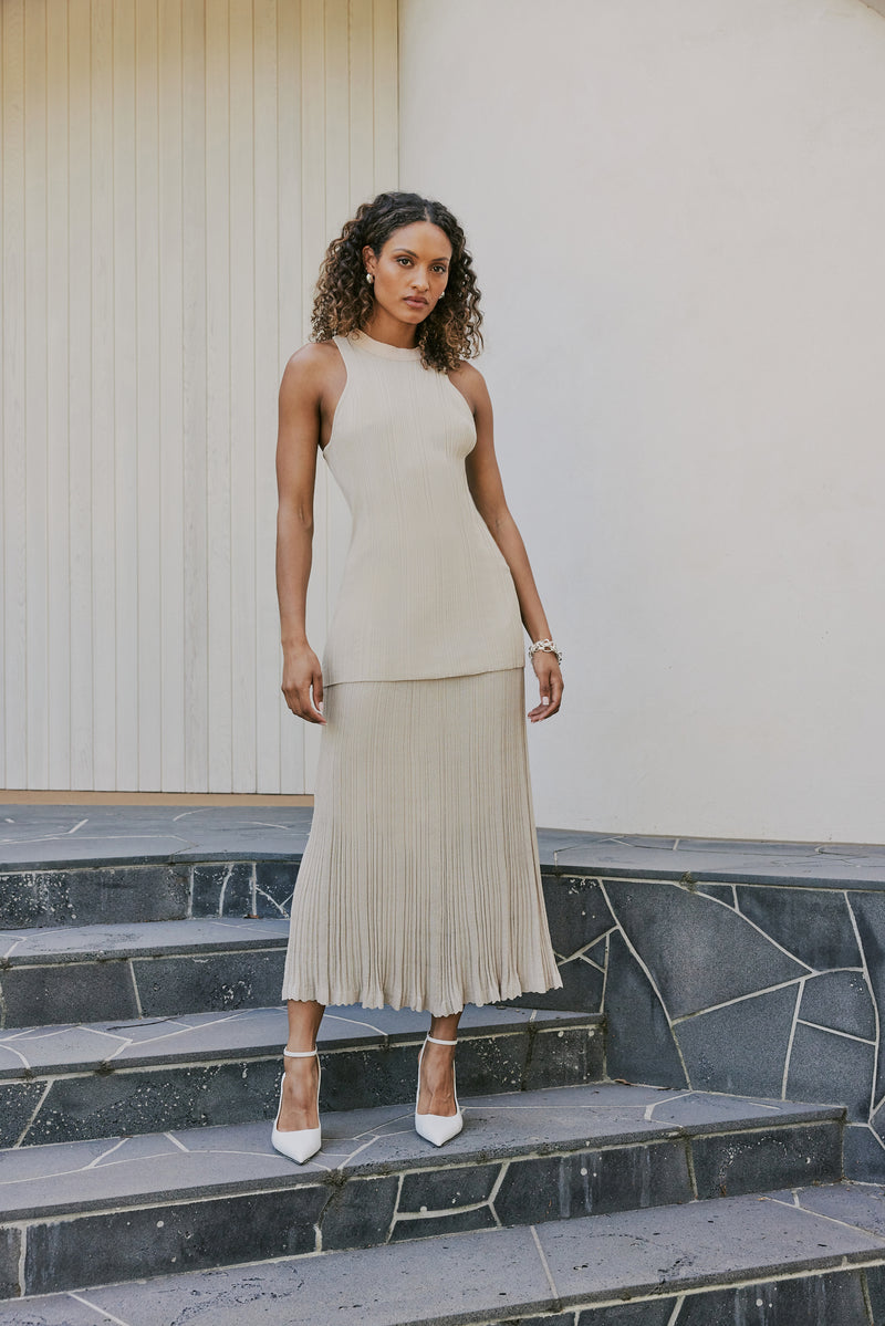 brunette model wears CURAAE Adelaid Midi Knit Pleated Swing Skirt In Oatmeal front shot