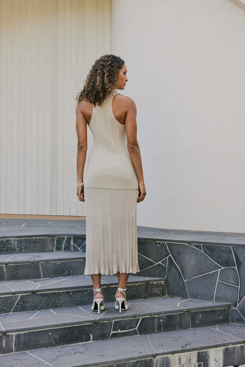 brunette model wears CURAAE Adelaid Midi Knit Pleated Swing Skirt In Oatmeal back shot