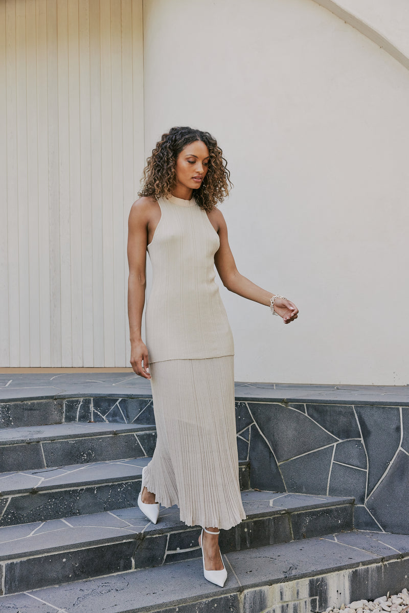 brunette model wears CURAAE Adelaid Midi Knit Pleated Swing Skirt In Oatmeal mood shot