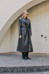 blonde model wears boots and leather mini dress and CURAAE Cameron Vegan Leather Fabric Tie Trench Coat In Chestnut side shot