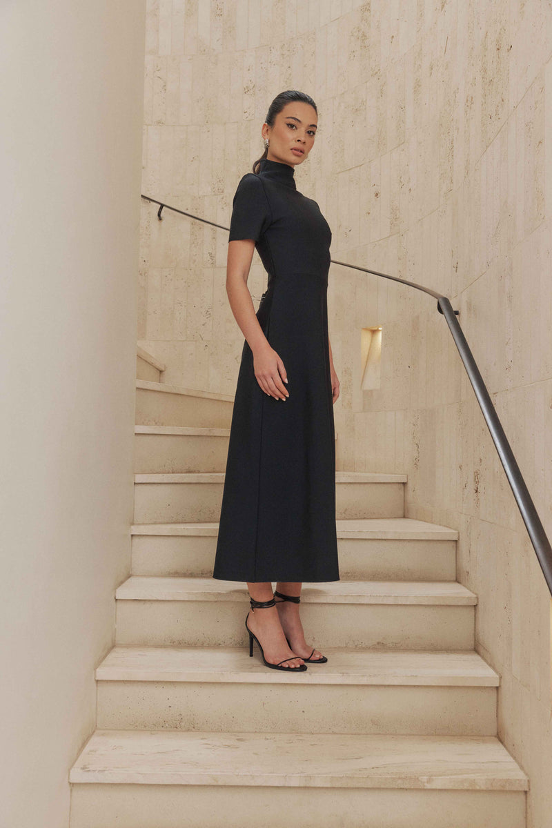 Brunette model wears Oscar Short Sleeve Midi Dress in Black side shot