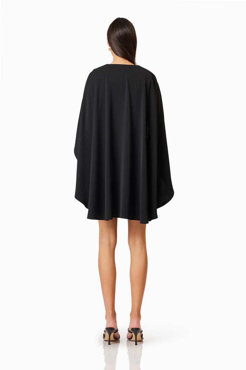 Brunette model wearing Lilydale Cape Mini Dress In Black back shot